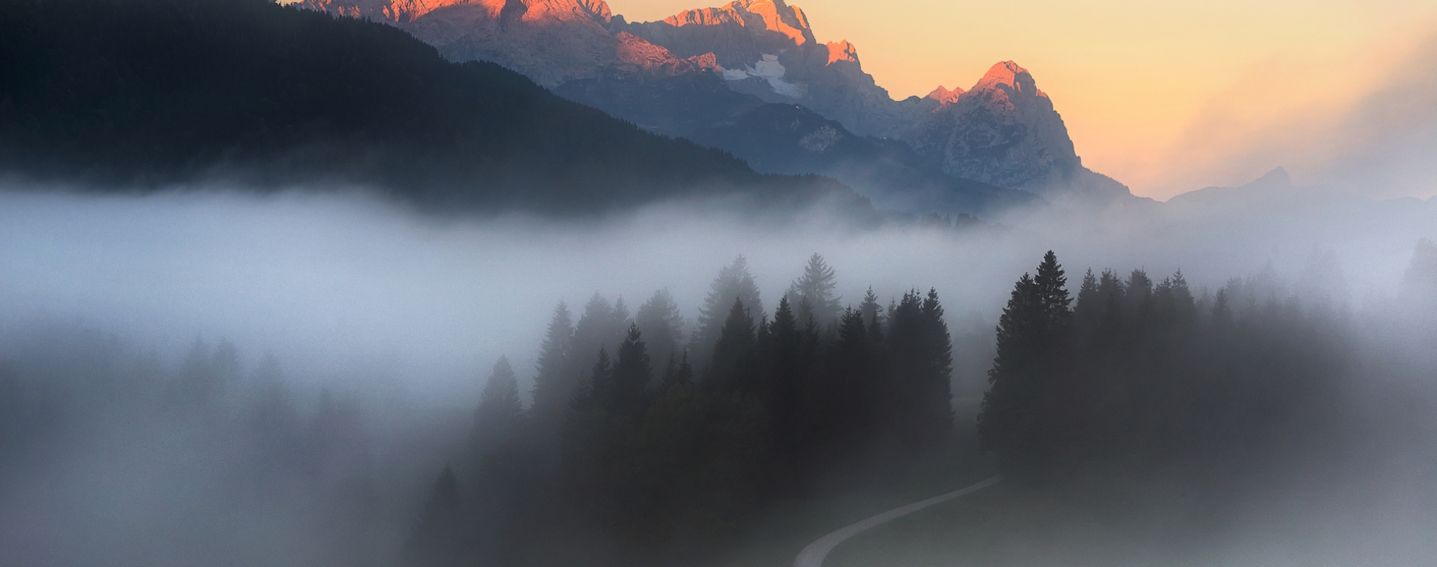 Calm and restful morning. Cloudy sky and foggy forest near beautiful lake. Bavarian Alps, Bavaria, Germany.